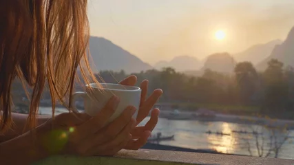 Fotobehang Chocoladebruin Young woman drinking hot coffee on the balcony with beautiful mountain landscape  © alexeg84