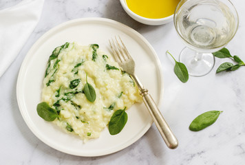 Gentle cream risotto with spinach, served with wine. Light background.
