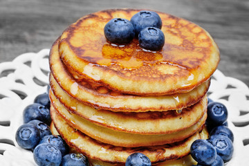 Pancakes with honey and blueberries in a plate on a wood table