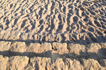 Old ancient yellow stone steps covered with brown friable sand with waves and irregularities,...