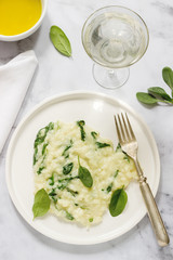 Gentle cream risotto with spinach, served with wine. Light background.