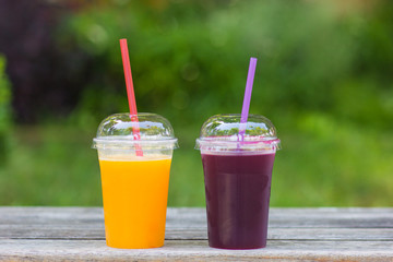 Freshly squeezed pomegranate and orange juice on a wooden surface, blurred background