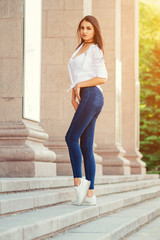 Obraz premium young stylish brunette girl posing in white shirt and jeans
