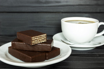 copy spaсe,  cup of coffee in a bowl with coffee beans on a dark wood background with chocolate waffles