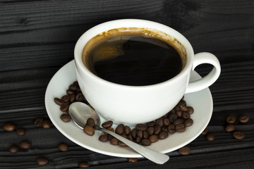  cup of coffee in a bowl with coffee beans on a dark background