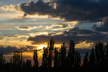 Landscape with dramatic light - beautiful golden sunset with saturated sky and clouds.