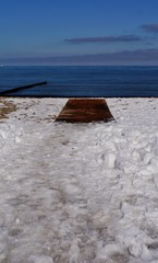 Fußspuren im Schnee zum Holzsteg am Meer