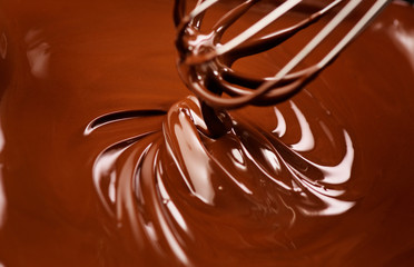 Chocolate. Mixing melted dark chocolate with a whisk. Closeup of liquid hot chocolate swirl. Confectionery