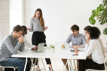 Serious businesswoman scolding employees for bad work results during company meeting, female team...