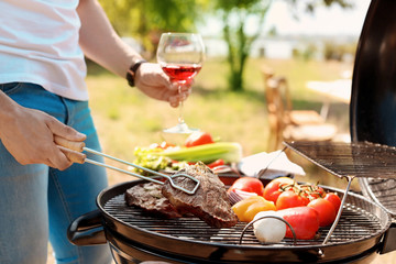 Man cooking meat and vegetables on barbecue grill outdoors