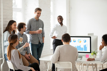 Multiracial work team having fun and laughing together during coffee break in coworking open space,...
