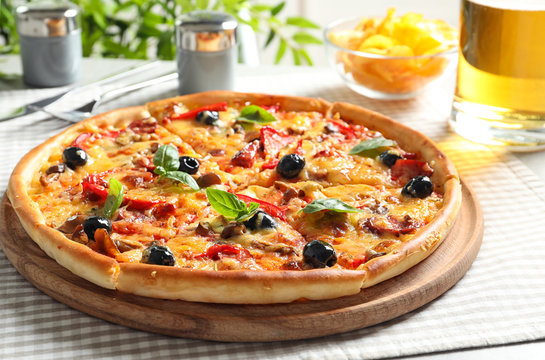 Delicious pizza with olives and sausages on table