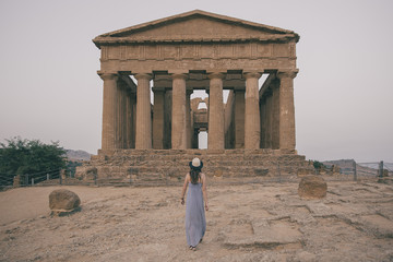 Young woman with hat backgards in Agrigento Temple at summer