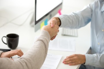 Naklejka na ściany i meble Close up of female employer shaking hand of male job applicant, congratulating with successful interview process, making deal, greeting client with handshake. Concept of cooperation, partnership, HR