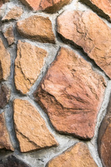 Decorative facade facing or original paved pathway close up, made as asymmetric mosaic of natural stone of different sizes and shapes.