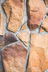 Decorative facade facing or original paved pathway close up, made as asymmetric mosaic of natural stone of different sizes and shapes.