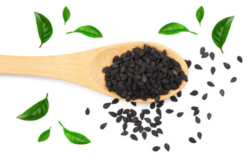 Black sesame seeds in a wooden spoon isolated on white background decorated with green leaves. Top view. Flat lay