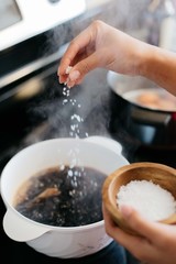 Hand sprinkling salt into boiling pot