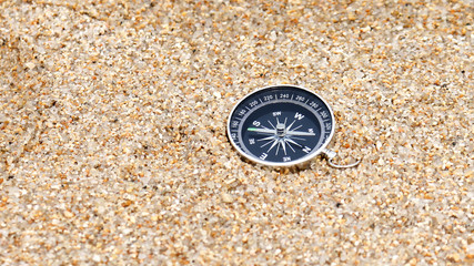 Close-up image of a compass on the sand.