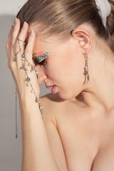 beauty girl with colorful make-up in jewelry looks down