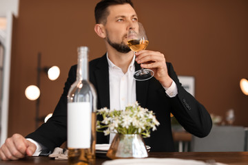 Man with glass of wine at table in restaurant
