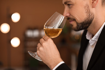 Young man with glass of wine indoors