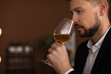 Young man with glass of wine indoors