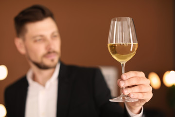 Young man with glass of wine indoors