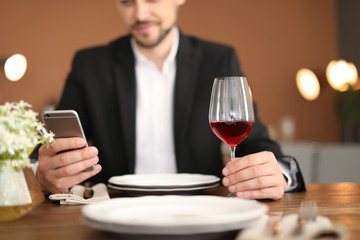 Man with glass of wine at table in restaurant