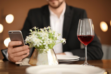 Man with glass of wine at table in restaurant