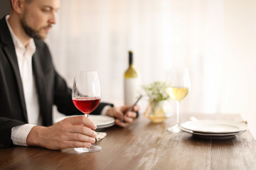 Man with glass of wine at table in restaurant