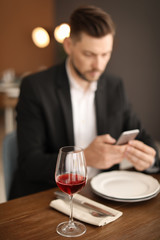 Man with glass of wine at table in restaurant