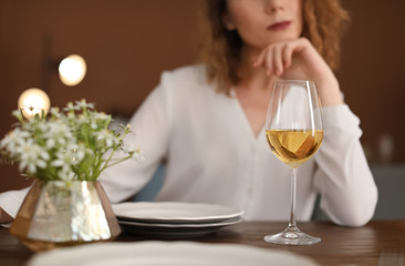 Woman with glass of wine at table in restaurant