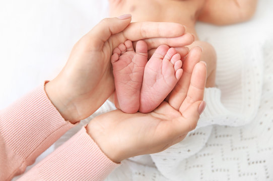 Mother holding little baby feet in hands