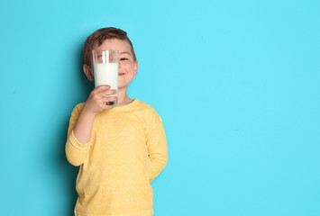 Cute little boy with glass of milk on color background
