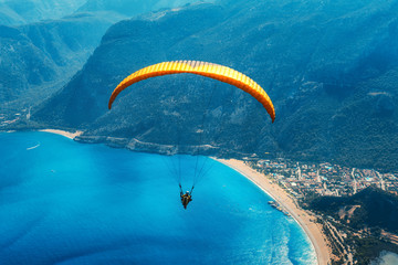 Paragliding in the sky. Paraglider tandem flying over the sea with blue water, beach and mountains...