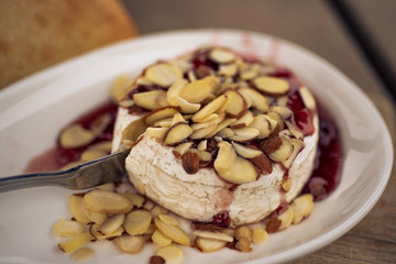 Baked Brie with Red Wine Jelly, Sliced Almonds French-Italian village Style dish on wooden board. Top -  above, close up view.