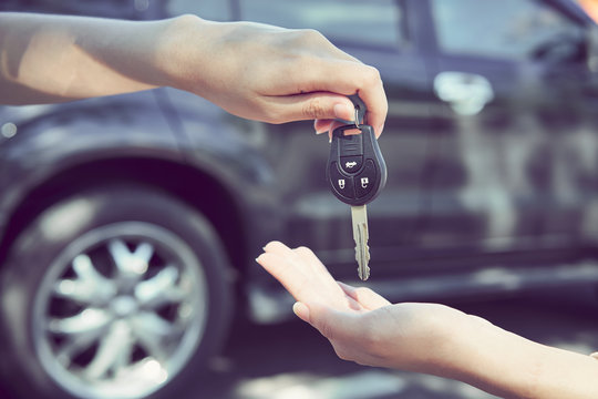 Woman's hand give the car key and blurred background.