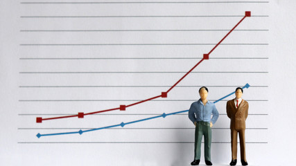 Two miniature men standing in front of a linear graph. The concept of increasing income gap.
