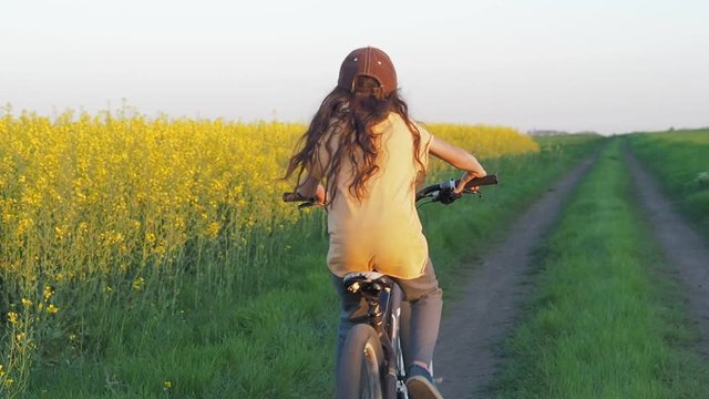 Child on a bicycle in the field. A girl with a bicycle in the countryside.