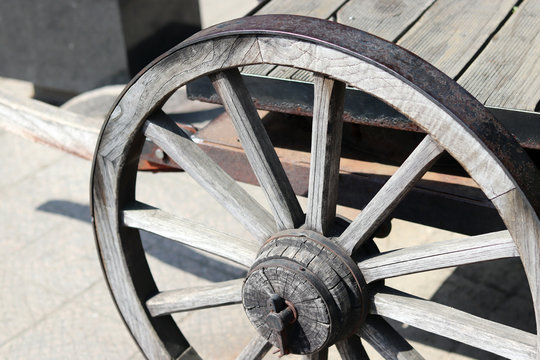 A partial image of a wagon with wooden wheels. 