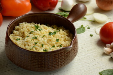 Bulgur in plate on wooden table. Traditional middle eastern or arab dish. Top view. vegetarian dinner. Bulgur  with vegetables, spices on white background. Flat la