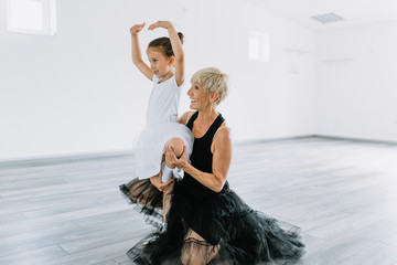 Charming senior ballet teacher learning little ballerina how to dance.