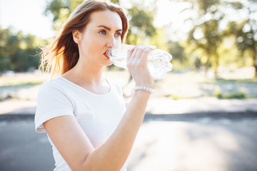 Young sports girl, drinking water from the bottle, after a hard workout, can be used for advertising, text insertion