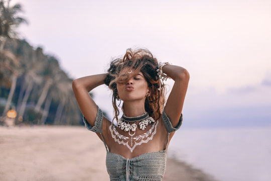 young beautiful boho woman sending air kiss on the beach at sunset