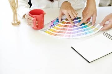 Graphic designer with interior design working on project of architecture drawing   and colour swatches, colour chart at studio workplace.
