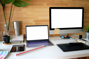 Workspace of Artis graphic designer with blank screen laptop and desktop computer.