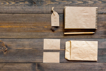 Fototapeta premium Mockup business brand template. Blank stationery and accessories made of craft paper for branding on dark wooden background top view mockup pattern copy space