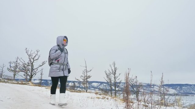 Travel of woman on ice of Lake Baikal. Close unique buddhist stupa burkhan monument symbol mystical historic ritual island Ogoi landscape mountains shamanic worship. Trip to winter island. Hiker wears