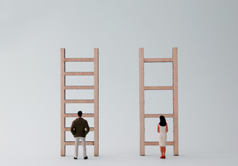Miniature men and women standing in front of different ladders. A gender discriminatory concept of...